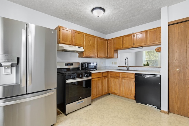 kitchen with appliances with stainless steel finishes, a sink, light countertops, brown cabinetry, and under cabinet range hood