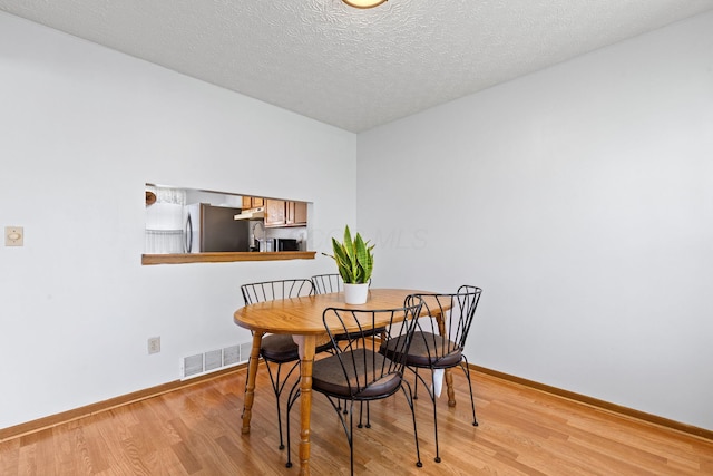 dining room featuring baseboards, visible vents, and light wood-style floors