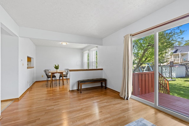 living area featuring baseboards, light wood-type flooring, and a textured ceiling
