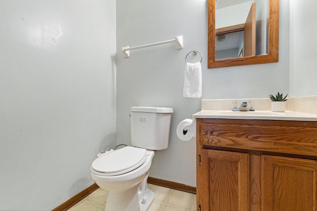 half bath with baseboards, vanity, and toilet