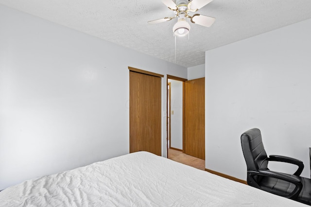 carpeted bedroom featuring baseboards, a textured ceiling, ceiling fan, and a closet
