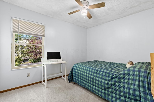 bedroom featuring baseboards, ceiling fan, carpet, and a textured ceiling