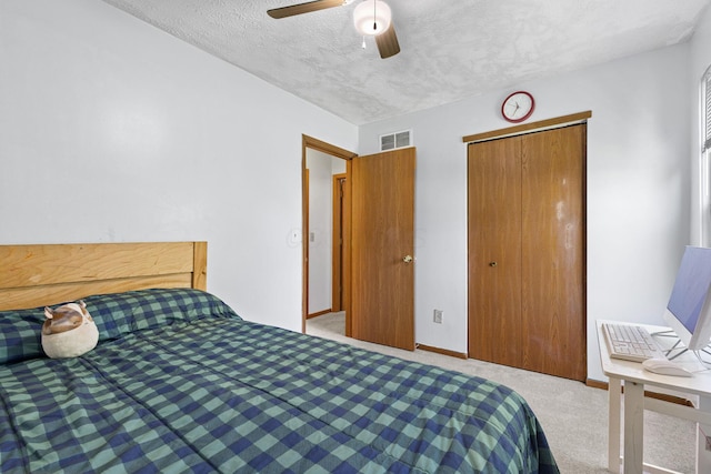bedroom featuring a ceiling fan, a textured ceiling, visible vents, a closet, and carpet