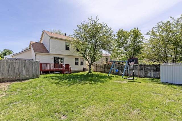 view of yard with a wooden deck, a fenced backyard, an outbuilding, a playground, and a storage shed