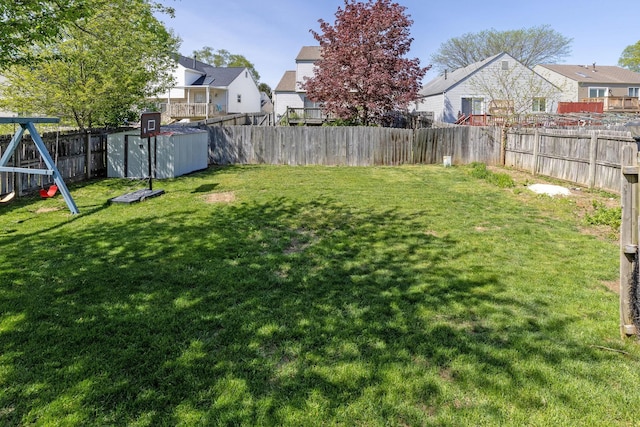 view of yard featuring a residential view, a storage unit, an outbuilding, and a fenced backyard