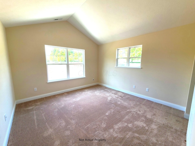 carpeted empty room featuring baseboards and lofted ceiling