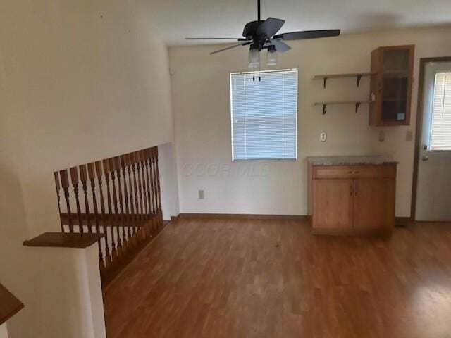 interior space featuring ceiling fan, baseboards, open shelves, and light wood-type flooring