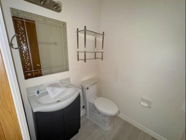 bathroom featuring toilet, wood finished floors, vanity, and baseboards