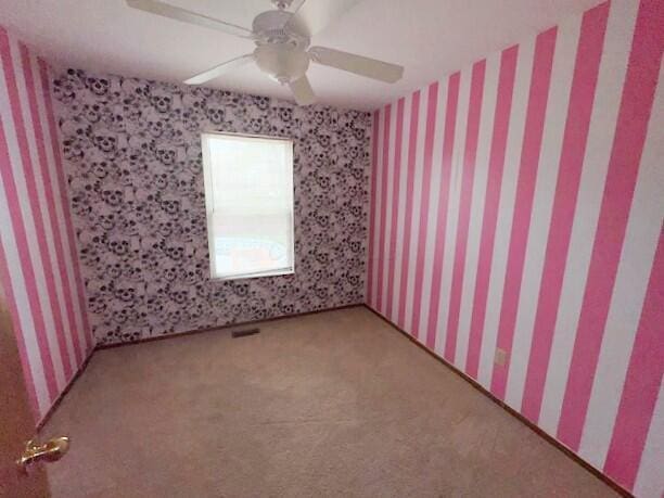 carpeted empty room with ceiling fan and wallpapered walls