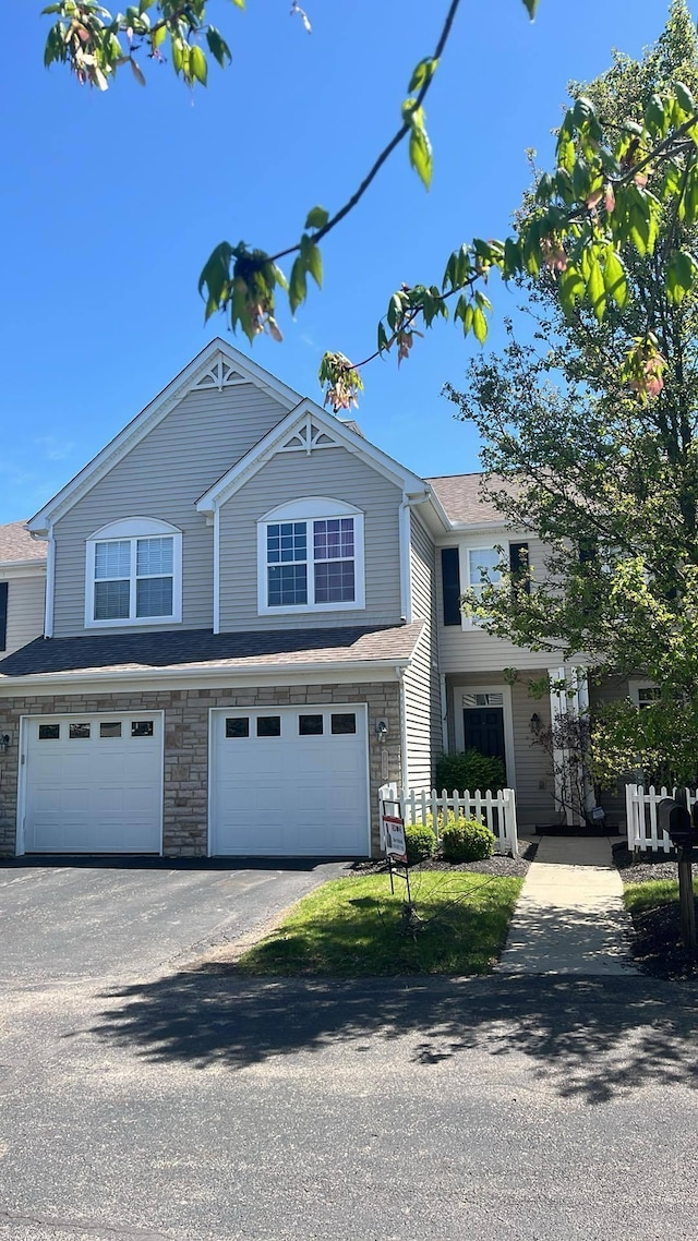 view of front of property with fence, an attached garage, and aphalt driveway