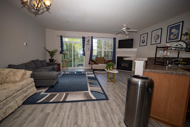 105 Autumn Ter SW, Etna, OH 43062 - living room with a fireplace with raised hearth, a textured ceiling, wood finished floors, and ceiling fan with notable chandelier