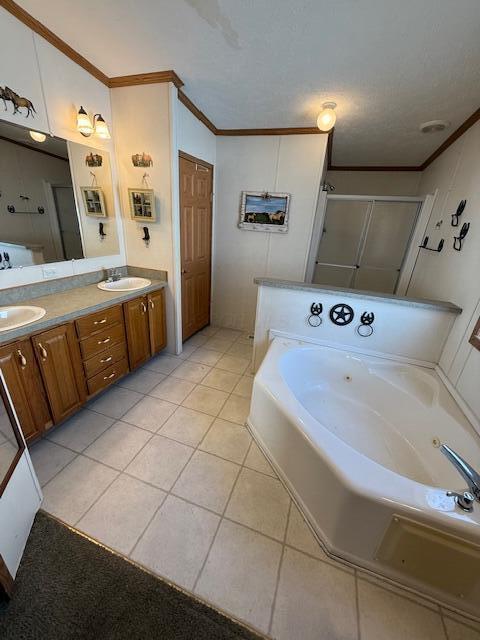 bathroom featuring tile patterned floors, a tub with jets, ornamental molding, and a sink