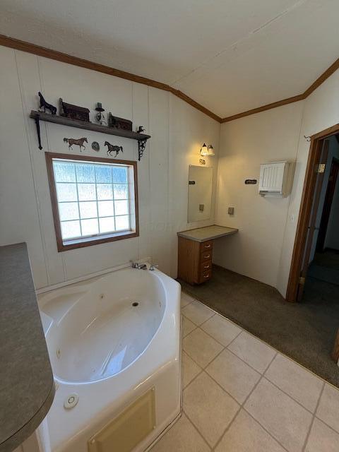 full bathroom featuring tile patterned flooring, vaulted ceiling, ornamental molding, vanity, and a jetted tub