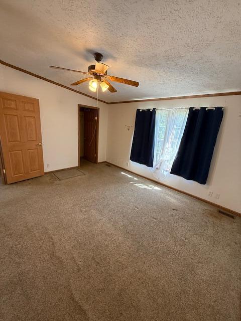 empty room featuring baseboards, ornamental molding, ceiling fan, and light colored carpet