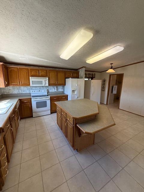 kitchen with a center island, light countertops, brown cabinets, and white appliances