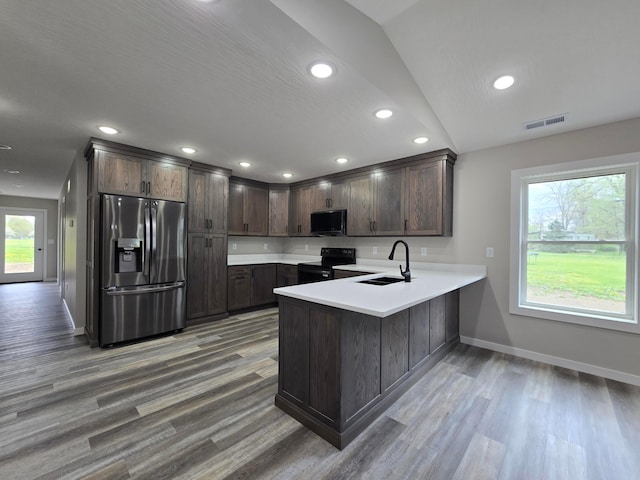 kitchen with a sink, a peninsula, baseboards, visible vents, and black appliances