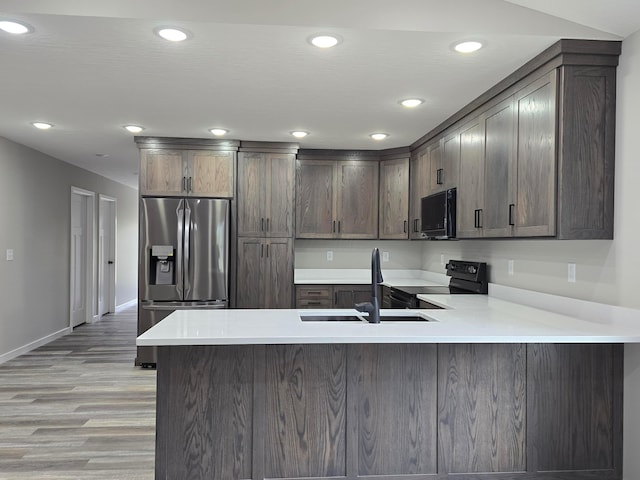 kitchen featuring recessed lighting, light wood finished floors, a peninsula, and black appliances