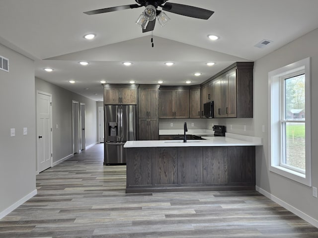 kitchen featuring a peninsula, a healthy amount of sunlight, dark brown cabinets, baseboards, and black appliances