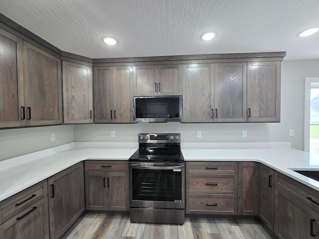 kitchen featuring light wood-type flooring, light countertops, appliances with stainless steel finishes, and dark brown cabinetry