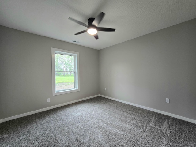 empty room with baseboards, a ceiling fan, dark carpet, and visible vents