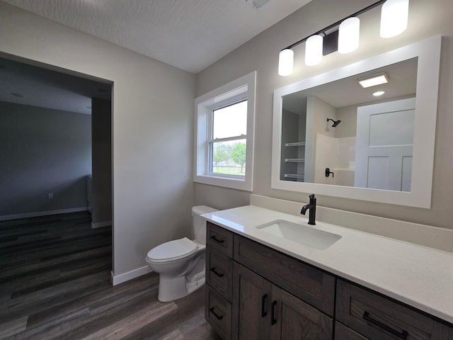 full bathroom featuring vanity, wood finished floors, toilet, baseboards, and walk in shower