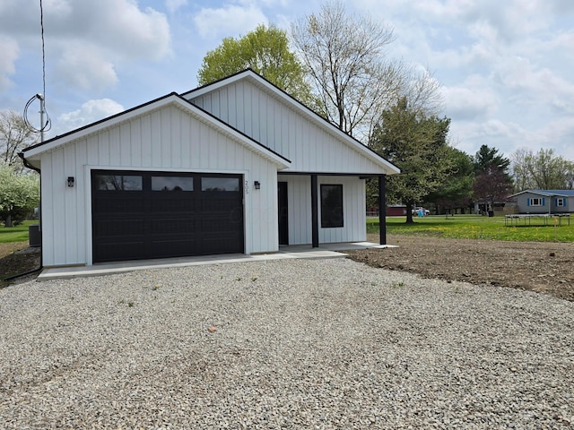 view of front facade with board and batten siding, an attached garage, and driveway
