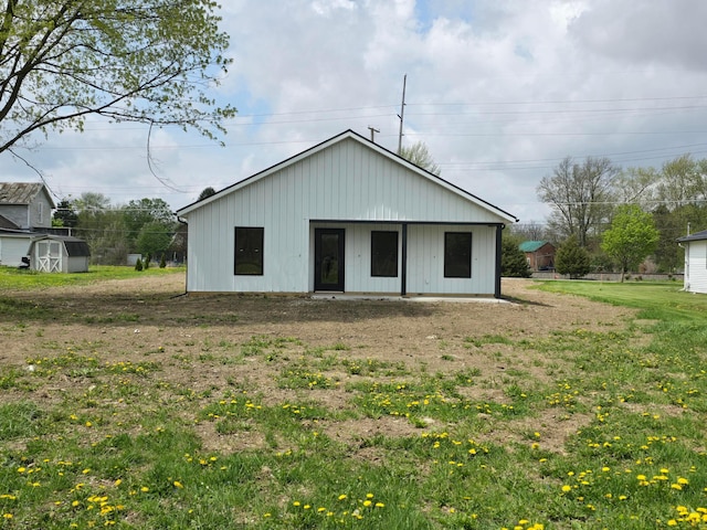 rear view of house with a lawn, an outdoor structure, and a storage unit