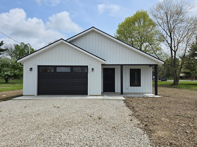 modern farmhouse featuring covered porch, board and batten siding, and gravel driveway