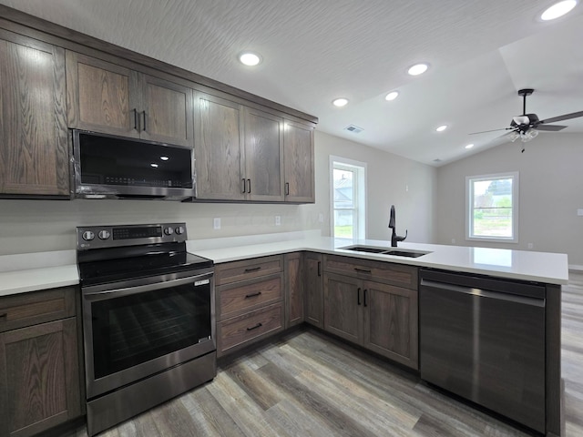 kitchen featuring a sink, light countertops, light wood finished floors, a peninsula, and stainless steel appliances