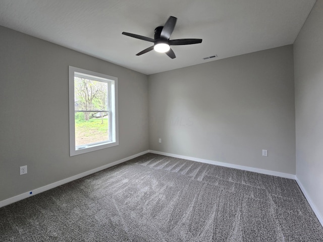 unfurnished room with baseboards, a ceiling fan, dark carpet, and visible vents