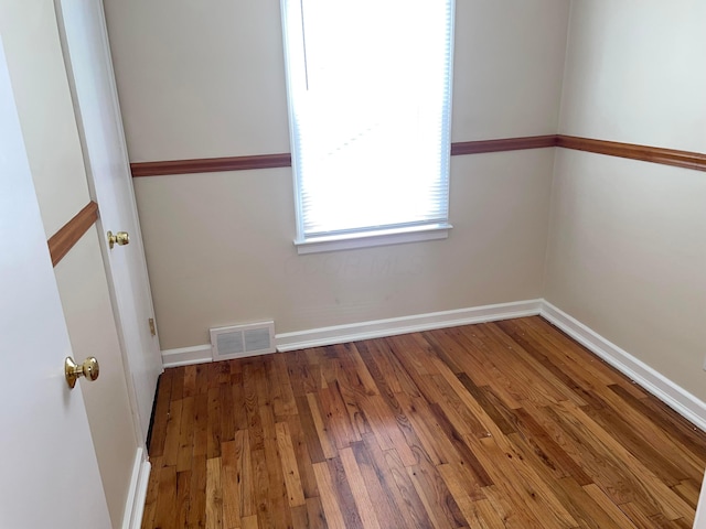 empty room with visible vents, baseboards, and wood finished floors