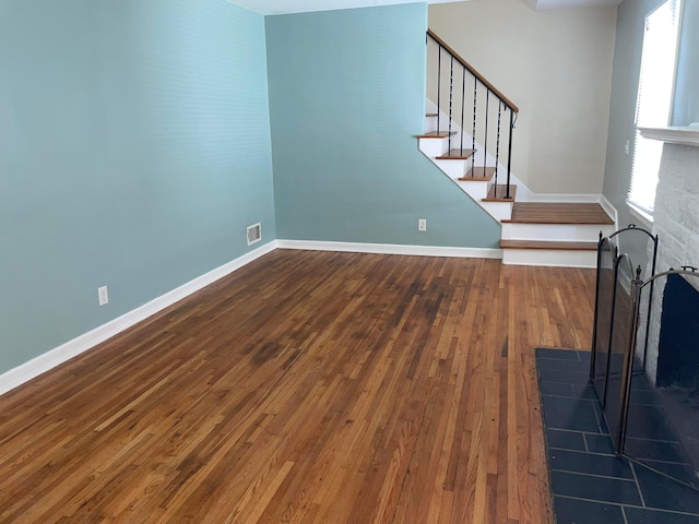 unfurnished living room with wood-type flooring, visible vents, and plenty of natural light
