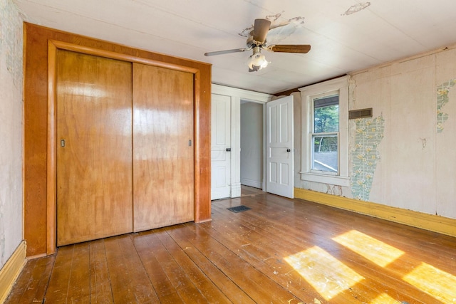 unfurnished bedroom with ceiling fan, a closet, and wood-type flooring