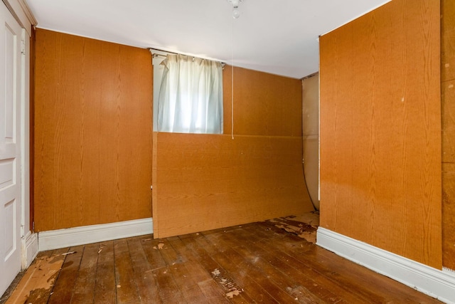 unfurnished room featuring hardwood / wood-style floors and wooden walls