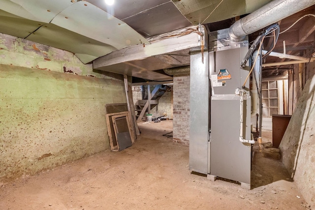 unfinished below grade area featuring heating unit and stairway