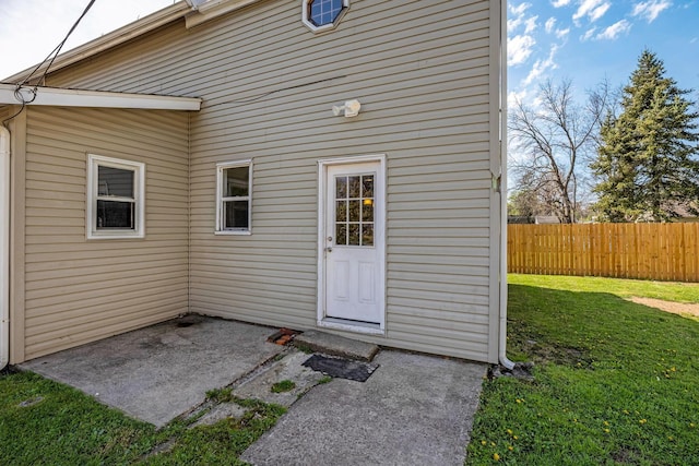 property entrance with a patio, fence, and a yard