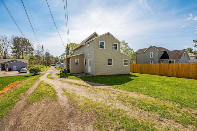 rear view of property featuring fence, dirt driveway, central air condition unit, and a lawn