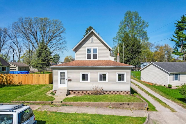 back of house featuring driveway, a yard, entry steps, and fence