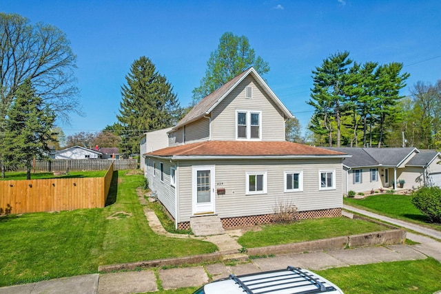 rear view of house featuring a yard, a shingled roof, entry steps, and fence