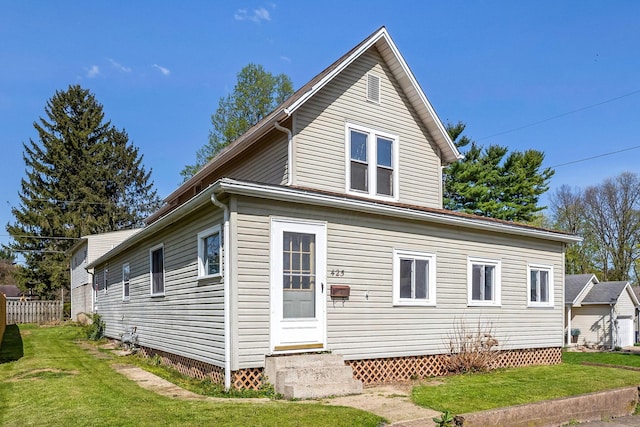 rear view of house featuring a yard, entry steps, and fence