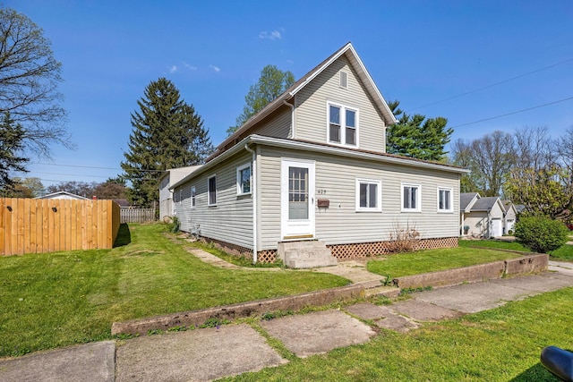 view of front of property featuring fence, entry steps, and a front lawn