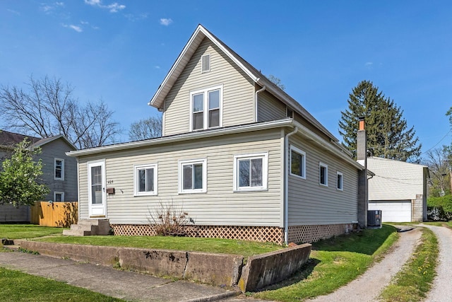 view of front of house featuring a detached garage, a front lawn, central AC, and entry steps
