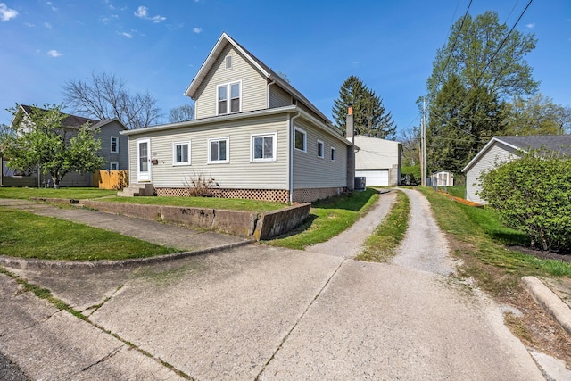 view of property exterior with a detached garage, entry steps, and driveway