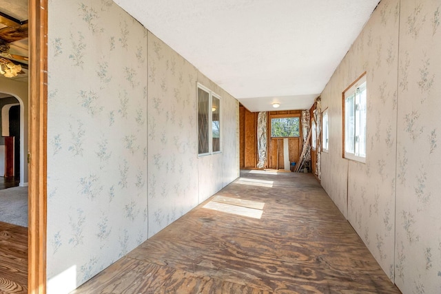 hallway with arched walkways and wallpapered walls