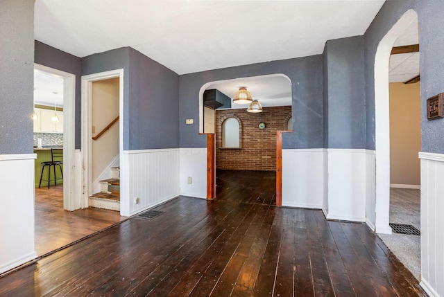 interior space featuring wood-type flooring, a wainscoted wall, and arched walkways
