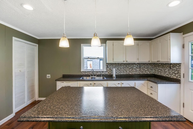 kitchen featuring a center island, dark countertops, decorative backsplash, and a sink