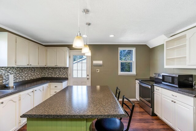 kitchen with a wealth of natural light, stainless steel appliances, dark countertops, and a kitchen island