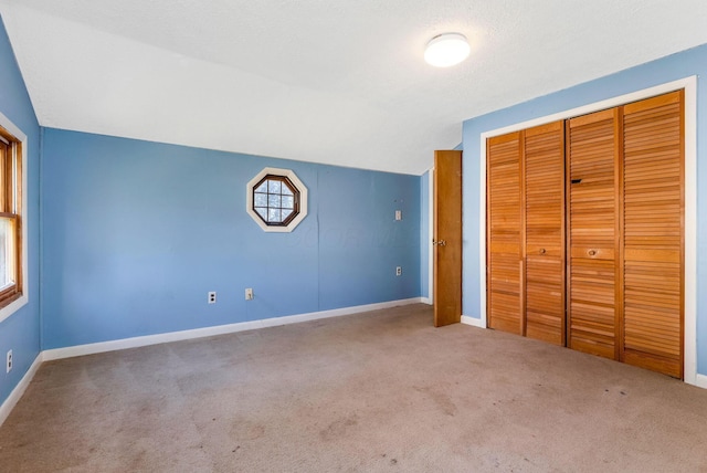 unfurnished bedroom with a closet, carpet floors, and baseboards
