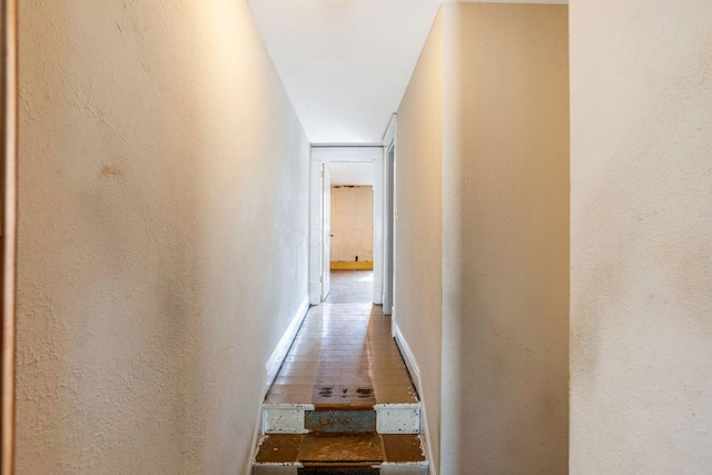 corridor featuring a textured wall and baseboards