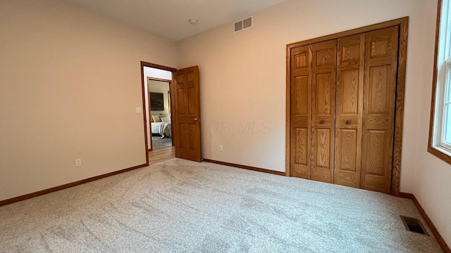 unfurnished bedroom with baseboards, visible vents, and carpet